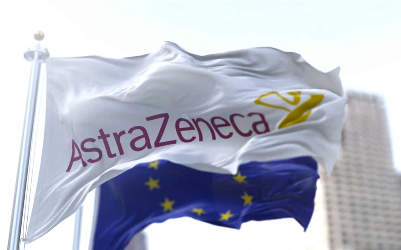 Bandiera bianca con il logo Astrazeneca che sventola con la bandiera europea sullo sfondo.